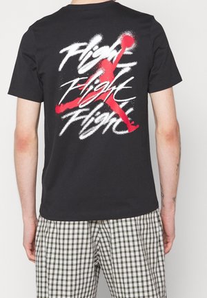 Black cotton t-shirt featuring a large red graphic of a jumping figure and stylized text "Flight" on the back. Short sleeves, crew neck.