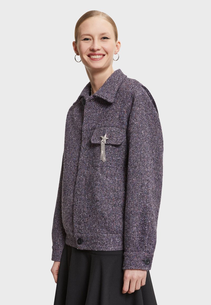 Lilla herringbone jakke med en knaplukning, brystlomme og en krystalnål som accent. Tekstur stof, let oversized pasform.