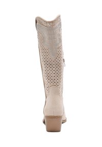 Botas de cowboy beige hechas de ante perforado con punta afilada. Presentan costuras decorativas y un tacón bajo de madera. Cierre con cremallera lateral.