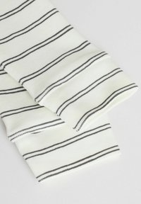 Tissu en coton à rayures blanches avec de fines rayures noires, présentant une texture douce et des bords roulés, affichant un design décontracté.