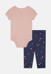 Rosa kurzärmliger Body mit Knopfverschluss hinten, kombiniert mit marineblauen Leggings mit einem verstreuten Erdbeer-Print in Rot und Pink.