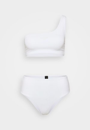Conjunto de bikini branco com top assimétrico e parte de baixo de alta cintura, textura suave, com um discreto detalhe do logótipo no centro.