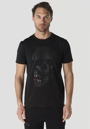 Hombre que lleva una camiseta negra con un diseño pixelado de calavera y texto que dice "It’s never too late" y "Tokyo Concept Brand Lab."