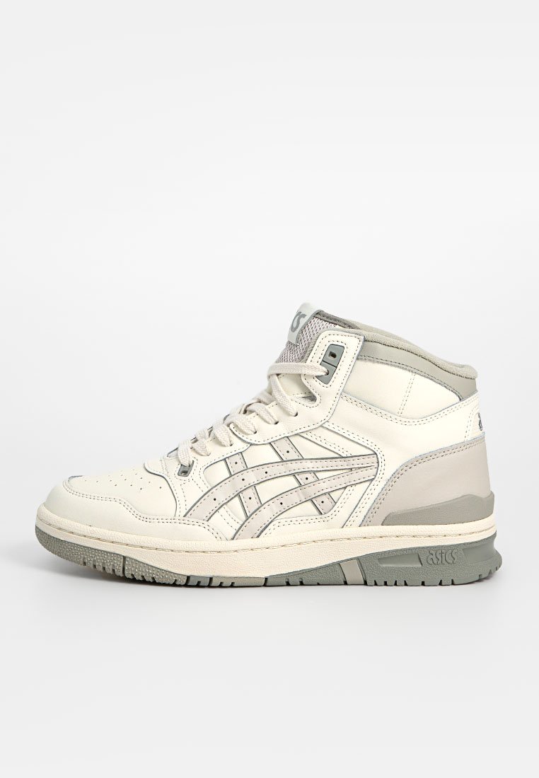 Chaussure de sport montante en blanc cassé et gris clair, dotée de matériaux en cuir et en maille, avec une semelle extérieure texturée et des accents de marque.
