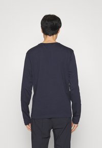 T-shirt à manches longues bleu marine en coton doux, avec un col rond et une coupe décontractée. Le dos présente une texture lisse et uniforme.