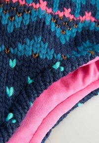 Tissu tricoté multicolore en bleu marine, bleu canard et rose, présentant un motif géométrique. La couche intérieure est en tissu rose lisse ; points de couture et textures visibles.