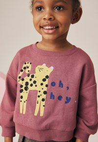 Sudadera burdeos con cuello redondo, que presenta un gráfico de leopardo amarillo y texto azul que dice "oh, hey". Tejido suave y corte holgado.