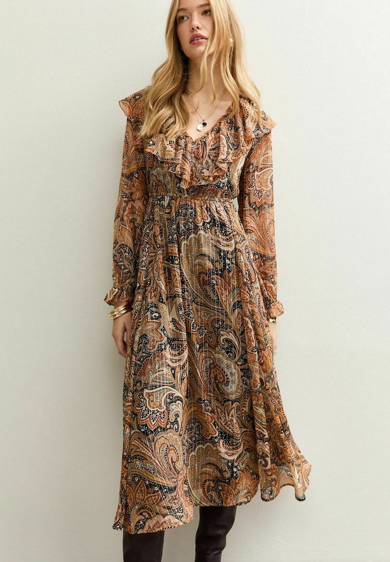 Lange paisley jurk in aardetinten van bruin, oranje en zwart. Beschikt over een ruches decolleté en lange mouwen, met een getailleerd ontwerp.