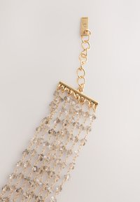 Gold-tone chain with a rectangular frame holding cascading clear crystals; features multiple strands for a layered look.