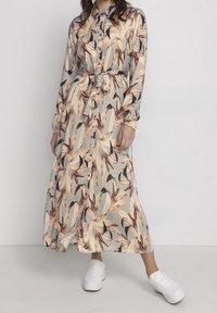 Langärmliges Hemdkleid aus hellgrauem Stoff mit einem Blumenmuster in Pfirsich und Dunkelbraun. Inklusive passendem Gürtel und Seitenschlitzen.