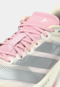 Ελαφρύ παπούτσι τρεξίματος με ροζ επάνω μέρος από δίχτυ, ασημί λεπτομέρειες και υφασμένο πέλμα. Διαθέτει εμφανές λογότυπο «ADIZERO» στο πλάι.