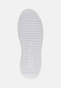 Semelle de basket blanche avec des rainures texturées, marquée du logo "GUESS" en relief au centre. Pointe arrondie avec une légère courbe au talon.