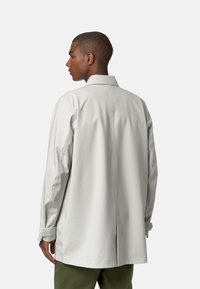 Giacca leggera grigia con vestibilità rilassata, colletto, maniche lunghe e spacchi laterali, realizzata in materiale liscio e resistente all'acqua.