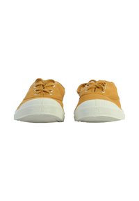 Des baskets en toile jaunes avec des semelles en caoutchouc blanches, un bout rond et un design classique à lacets avec des œillets métalliques.