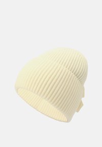 Kremowy, prążkowany beanie z podwinięciem i małą metką na białym tle.