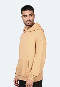 Felpa con cappuccio in beige chiaro, con tasca frontale, polsini a costine e una vestibilità comoda. Realizzata in morbido cotone.