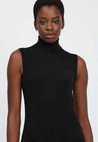 Top nero senza maniche in maglina liscia, con collo alto e design aderente che mette in risalto il torso.
