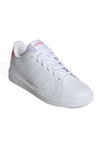 Zapatilla blanca con acentos en rosa, hecha de material sintético. Presenta un diseño de franjas perforadas y un cierre de cordones, suela plana de goma.
