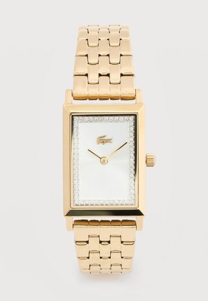 Guld rektangulært armbåndsur med ledet metalrem, hvid urskive, krystalramme, minimalistiske visere og lille krokodillelogo klokken 12.