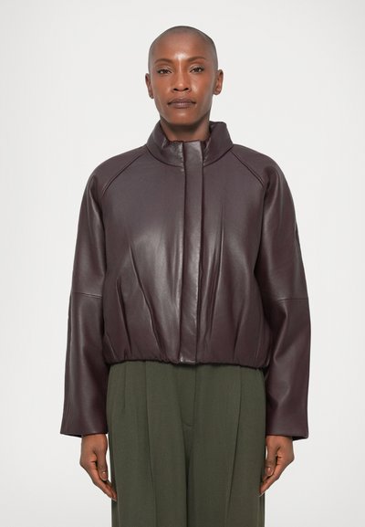 Giacca bomber in pelle bordeaux con alto colletto, orlo a coste e spalle cadenti. Texture liscia con una sottile lavorazione a cucito.