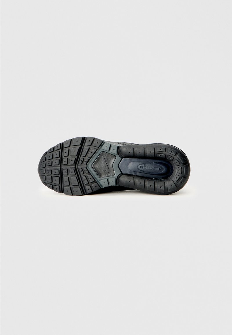 Suela de zapatilla deportiva negra con una superficie de goma texturizada, que presenta un patrón hexagonal y un talón reforzado para mayor estabilidad.