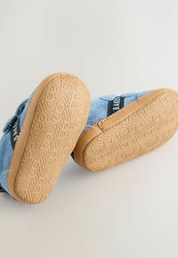 Scarpe in camoscio blu con suola in gomma color naturale caratterizzata da un motivo a zigzag testurizzato. Cinturino a strappo blu brillante sul lato con etichetta nera.