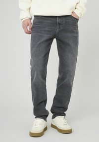 Jean en denim gris foncé avec une coupe droite, un léger délavage, cinq poches et des passants de ceinture, associé à des baskets blanches.