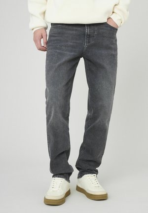 Jean en denim gris foncé avec une coupe droite, un léger délavage, cinq poches et des passants de ceinture, associé à des baskets blanches.