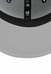 Gray fabric cap with a black brim, featuring a textured design and embroidered purple accents. Adjustable strap in the back.