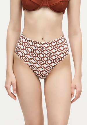 Žena nosiaca plavkové nohavičky s vysokým pásom s hnedo-bielym geometrickým vzorom a zodpovedajúci hnedý rebrovaný vrchný diel bikin.