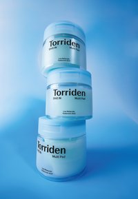 En stak af tre klare glas mærket "Torriden DIVE IN Multi Pad." Glassene har lyseblå låg, gennemskinnelige kroppe og fed sort tekst.