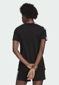 Schwarzes Sportshirt mit kurzen Ärmeln, das weiße Akzente an den Schultern aufweist. Glattes Material mit einem klassischen Rundhalsausschnitt und lockerer Passform.
