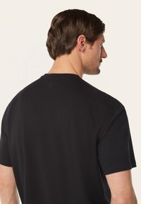 Zwarte t-shirt met korte mouwen, ronde hals, gemaakt van soepel katoen en voorzien van een klein logo detail op de achterkant van de hals.