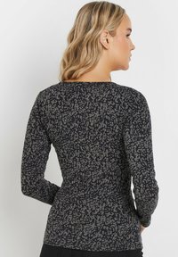Maglietta a maniche lunghe di colore grigio scuro, con motivo testurizzato in un grigio più chiaro. Design aderente con scollatura rotonda. Tessuto morbido e elasticizzato.