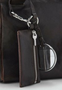 Borsa in pelle nera con zip argentata e portachiavi. Presenta una piccola tasca attaccata e un accento con specchio rotondo. Tessuto liscio.