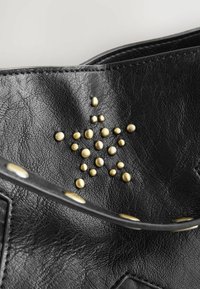 Čierna kožená kabelka s nitmi v tvare hviezdy v zlatej farbe, hladkou textúrou a kontrastným remienkom s kruhovými ozdobami.