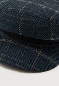 Villapipo tummansinisellä ruutukuviolla ja beigeillä yksityiskohdilla. Varustettu punottu musta nauha ja pyöreä, muotoiltu lippa.