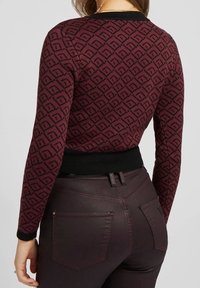 Maroon-värinen kuvioitu villapaita mustilla korosteilla; istuva malli, pyöreä kaula-aukko, pitkät hihat ja kontrastina musta vyötäröosa.