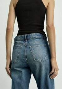 Denim jeans v svetlo modri barvi, z visokim pasom, petimi žepi in sproščenim krojem. Material ima mehak texture z rahlim zbledelostjo.