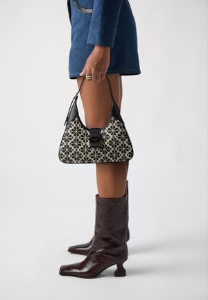 Black and cream handbag with floral pattern, rectangular shape, and a clasp closure. Worn with knee-high brown leather boots.