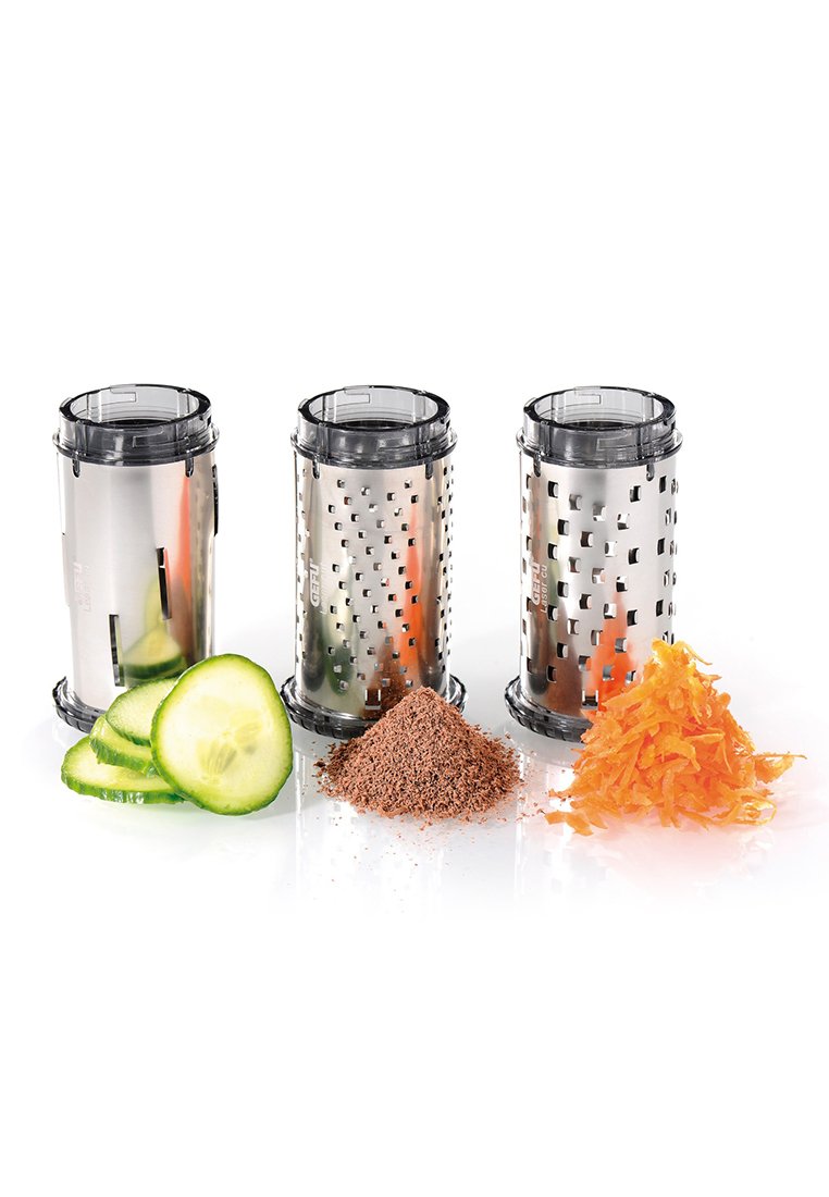 Tre cilindri di grattugia in metallo con coperchi trasparenti, che mostrano cetriolo affettato, scaglie di cioccolato e carote grattugiate.