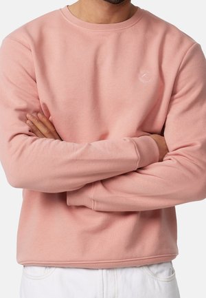 Felpa rosa chiaro con colletto e polsini a coste, dotata di un piccolo logo sul petto. Materiale in cotone, vestibilità rilassata e maniche lunghe.