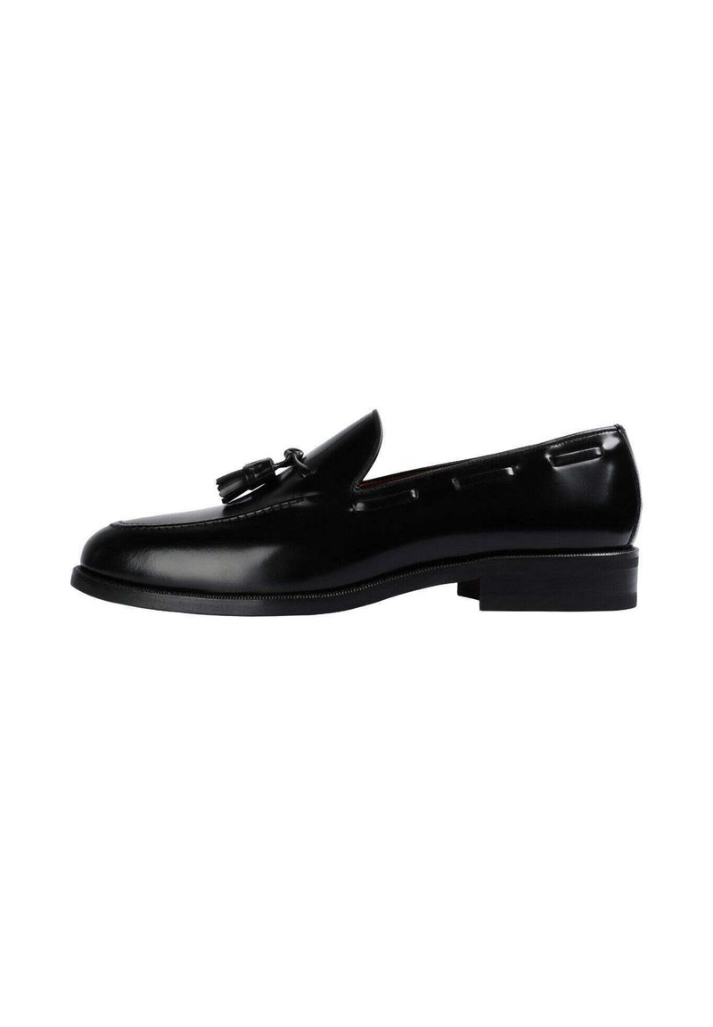 Mocasines de cuero negro con un acabado suave, detalles de borlas y un tacón rectangular bajo. Diseño clásico con acentos de costura lateral.