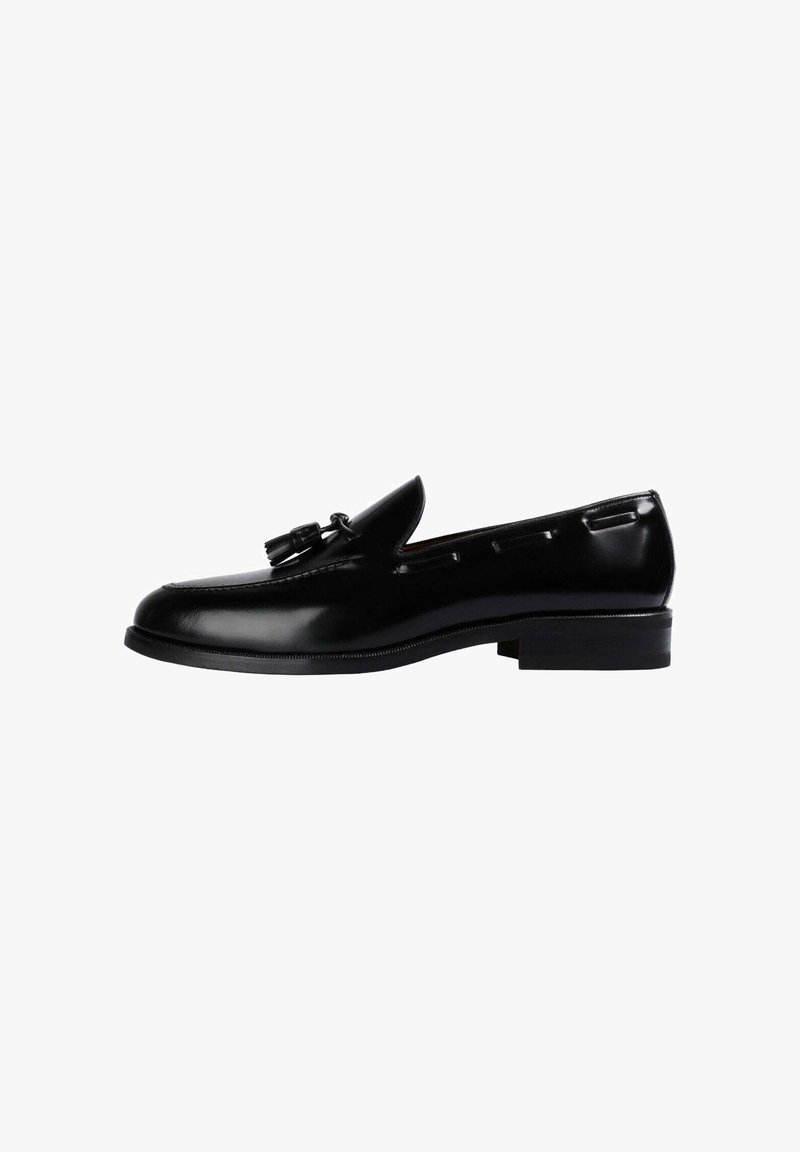 Mocasines de cuero negro con un acabado suave, detalles de borlas y un tacón rectangular bajo. Diseño clásico con acentos de costura lateral.