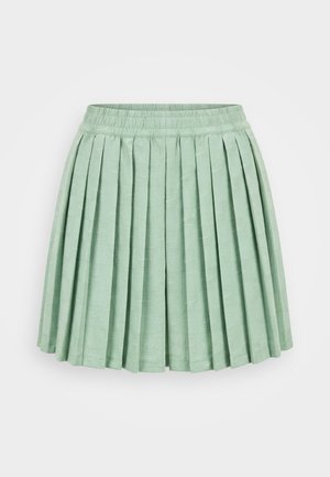 Jupe plissée vert clair avec taille élastique et motif carré texturé subtil sur tissu, sur fond uni.