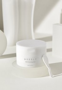 Valkoinen puhdistusbalsamipurkki, jossa on sileä, kiiltävä pinta. Etiketissä lukee "NEEDLY Mild cleansing balm". Mukana sopiva lasta. 120 ml.