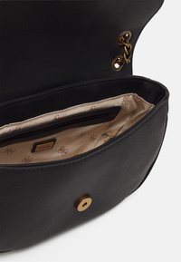 Musta nahkainen käsilaukku, jossa on kultaiset yksityiskohdat ja sisäinen vetoketjupusse. Sisävuori on hienolla kuviollisella kankaalla. Pyöreä sulkemisosa.