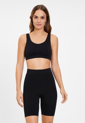 Black sports bra with a scoop neckline and gathered detail, paired with high-waisted black bike shorts featuring a smooth, stretchy fabric.