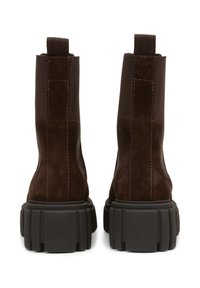 Stivaletti in suede marrone con una suola platform nera robusta, linguetta sul retro e dettagli di cucitura a contrasto.