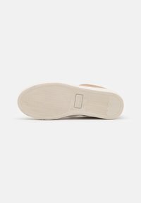 Schuhsohle aus strukturiertem Gummi, hellbeige Farbe und subtilem Wellenmuster. Verfügt über ein oberes aus glattem beigen Leder mit minimalen Details.